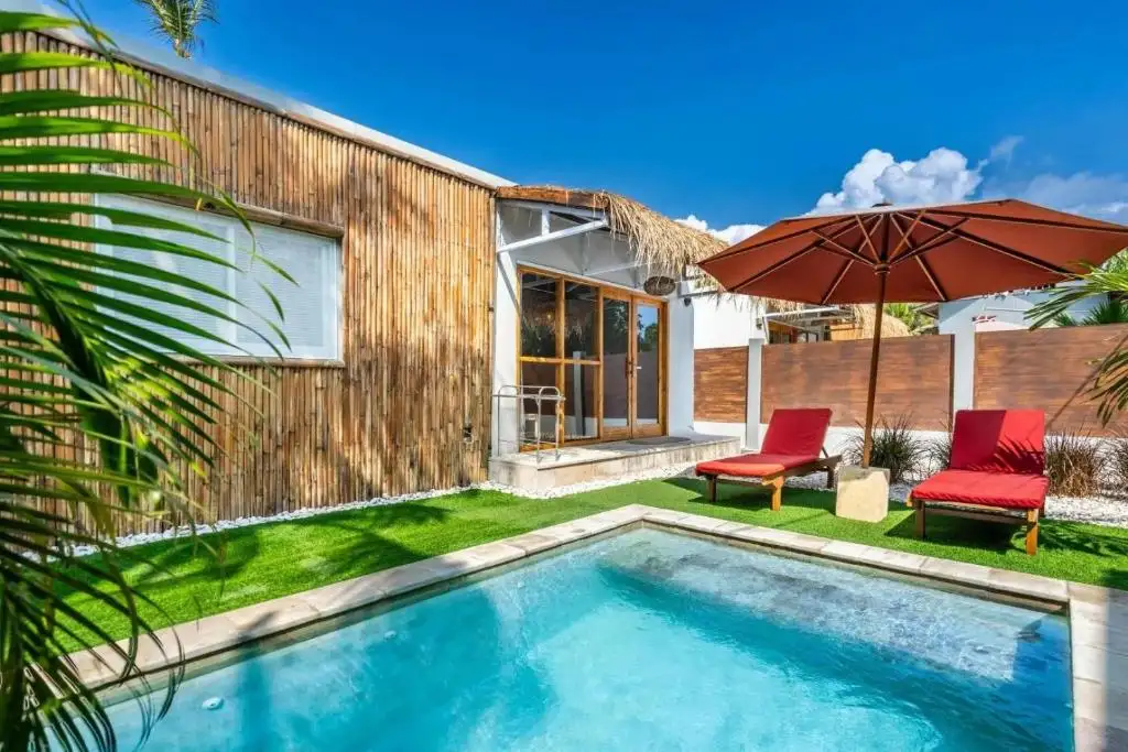 Private pool, red parasol and bamboo villa under a blue sky