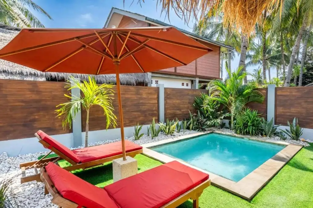 Teak loungers with red cushions next to the pool